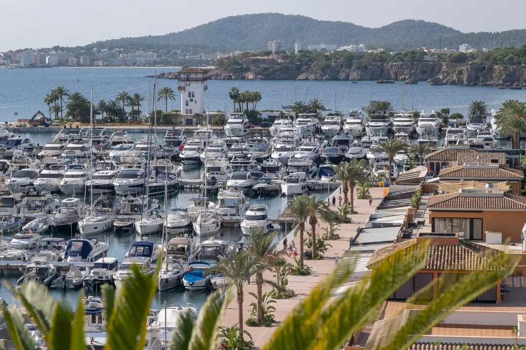 Puerto Portals marina view with luxury yachts and waterfront promenade, seen from apartment for sale in Mallorca.